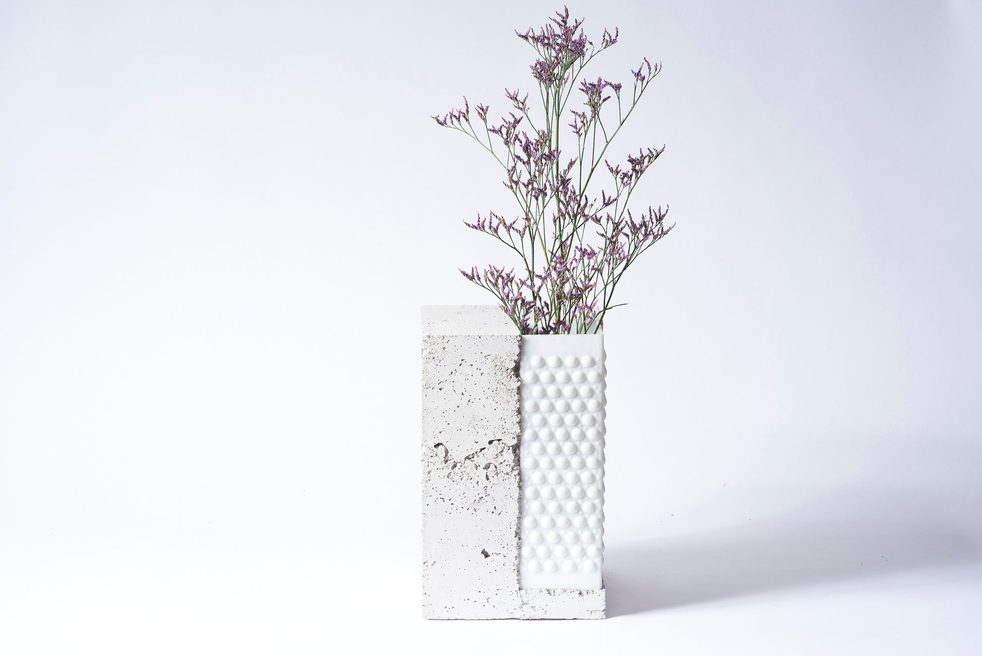 Bright stabel vase from Prasklo made from up-cycled glass material, a white chandelier, and cement, concrete. Individual single art piece