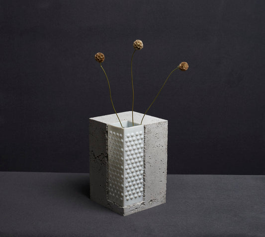 Bright stabel vase from Prasklo made from up-cycled glass material, a white chandelier, and cement, concrete. Individual single art piece