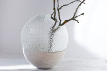Načíst obrázek do prohlížeče Galerie, a large ball vase made out of recycled glass and raw concrete set in white minimalistic interior on a table with decent flower.
