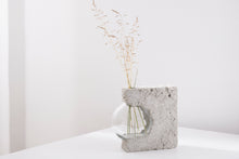 Load image into Gallery viewer, a vase made out of recycled glass and raw concrete set in white minimalistic interior on a table with decent flower.
