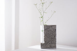 a vase made out of recycled glass and raw concrete set in white minimalistic interior on a table with decent flower. Art vase created by the Prague artist Petra Svejdarova a.k.a. Prasklo. Used materials are recycled glass and raw concrete without any plastificators.